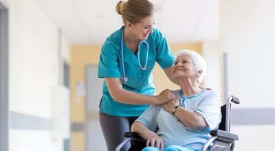 Ältere Dame im Rollstuhl mit Krankenschwester