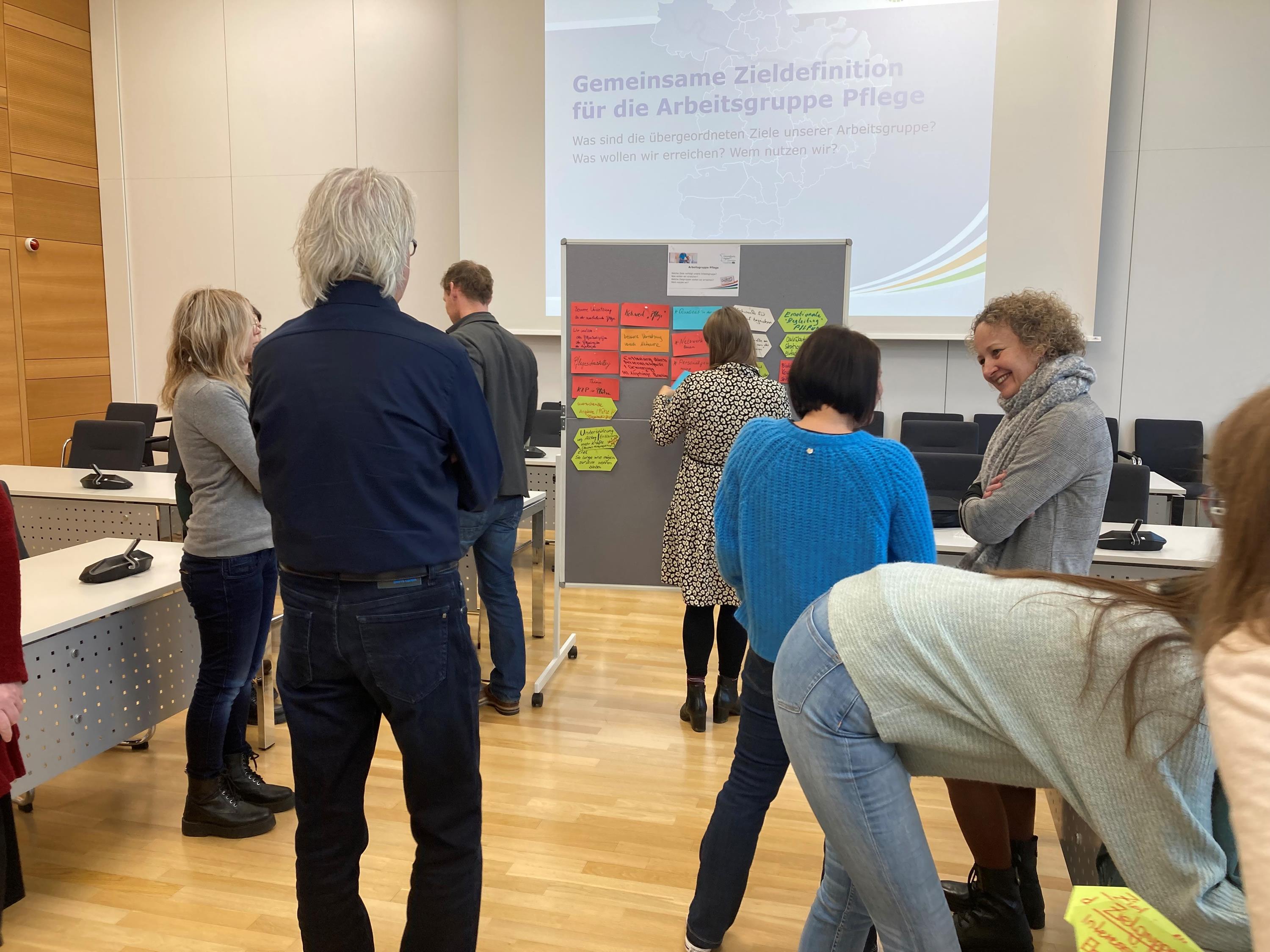 Menschen stehen vor Flipchart im Sitzungsraum